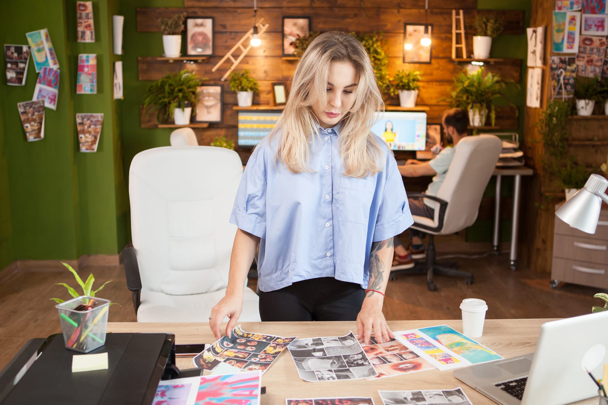 designer-feminina-caucasiana-verificando-os-projetos-de-seus-internos-homem-trabalhando-no-laptop-em-segundo-plano